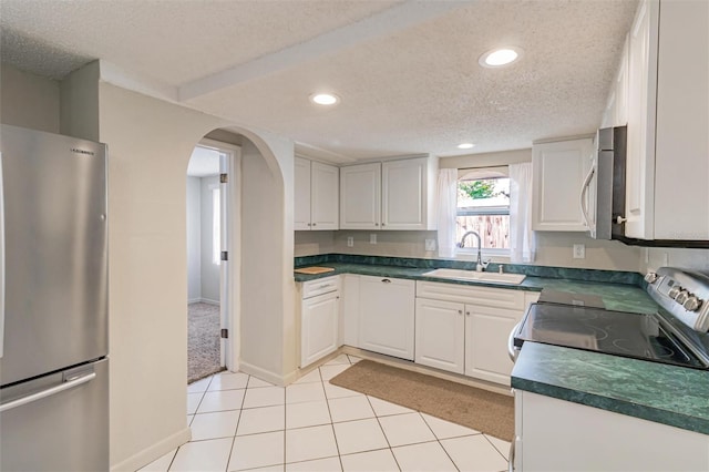 kitchen with a textured ceiling, stainless steel appliances, white cabinetry, and sink