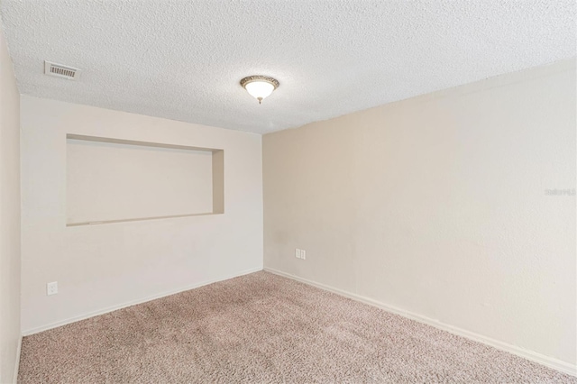 carpeted empty room featuring a textured ceiling