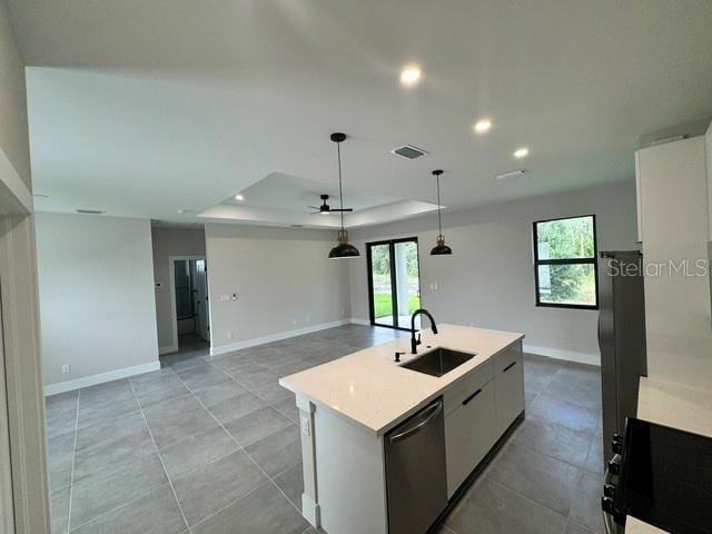 kitchen with white cabinets, sink, a tray ceiling, a kitchen island with sink, and stainless steel dishwasher