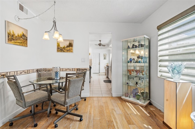 dining room with ceiling fan with notable chandelier and light hardwood / wood-style floors