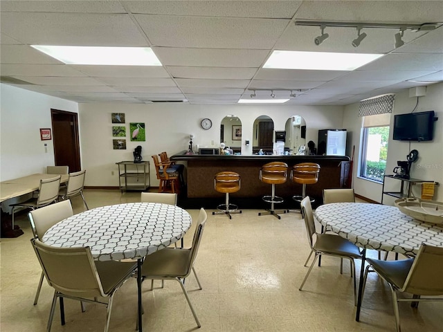 dining space featuring bar area, a paneled ceiling, and track lighting