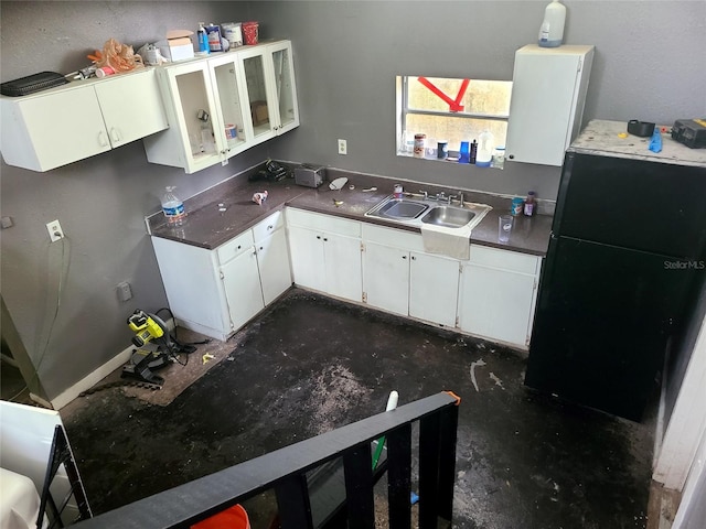 kitchen featuring sink, black fridge, and white cabinetry