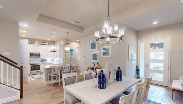 dining area featuring an inviting chandelier, sink, and light hardwood / wood-style floors