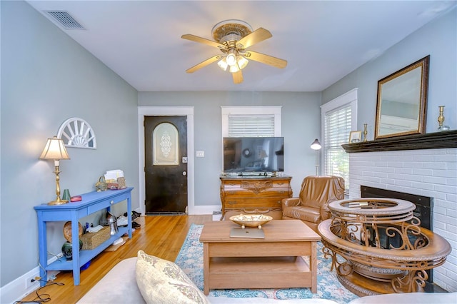 living room with ceiling fan, a fireplace, and light hardwood / wood-style flooring