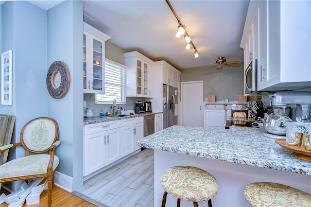 kitchen with appliances with stainless steel finishes, light hardwood / wood-style floors, kitchen peninsula, ceiling fan, and white cabinets