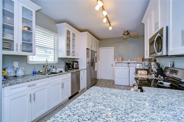 kitchen featuring white cabinetry, washing machine and clothes dryer, stainless steel appliances, sink, and ceiling fan