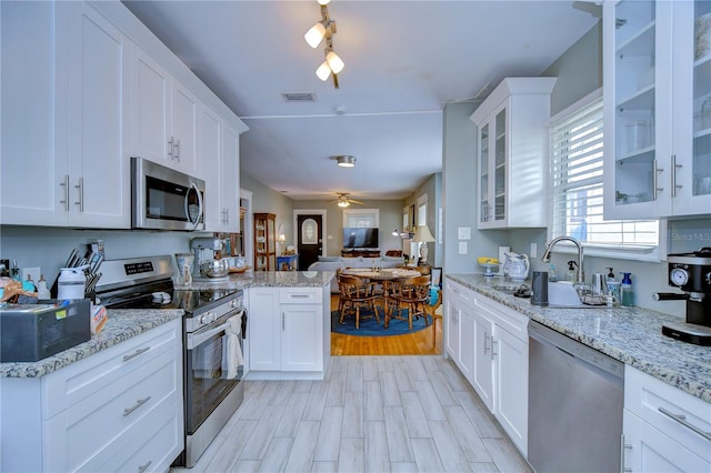 kitchen with white cabinetry, kitchen peninsula, stainless steel appliances, and ceiling fan