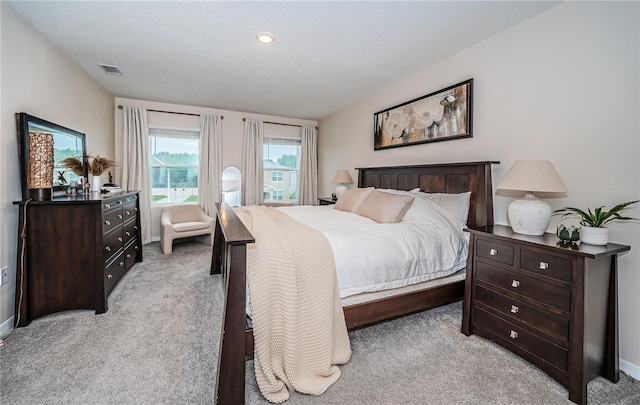 bedroom with light colored carpet and a textured ceiling