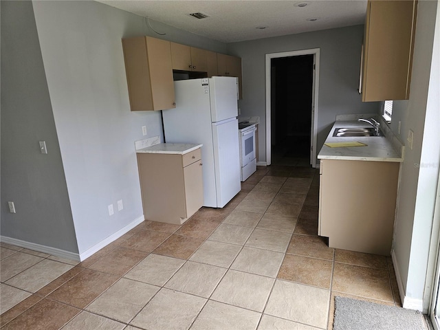 kitchen with cream cabinetry, white appliances, light tile patterned floors, and sink