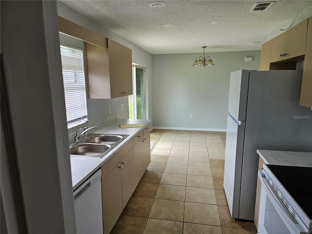 kitchen featuring white appliances, a textured ceiling, decorative light fixtures, an inviting chandelier, and sink