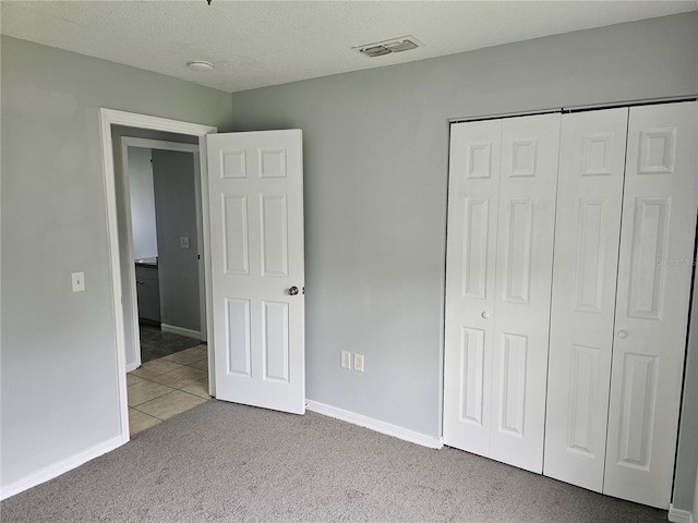 unfurnished bedroom with light carpet, a textured ceiling, and a closet