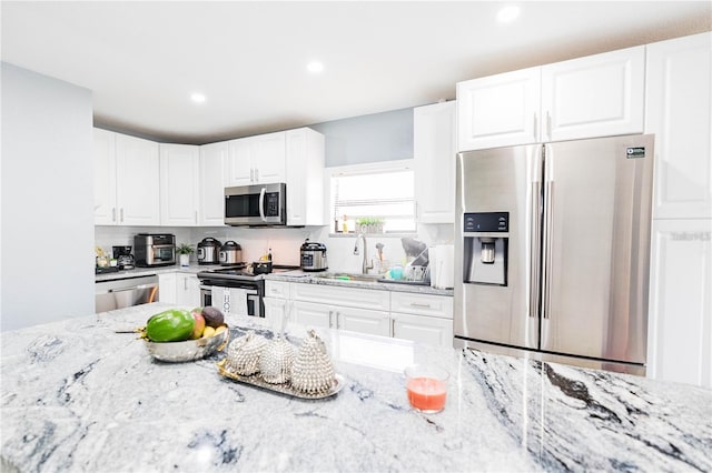 kitchen with white cabinets, light stone countertops, sink, and appliances with stainless steel finishes