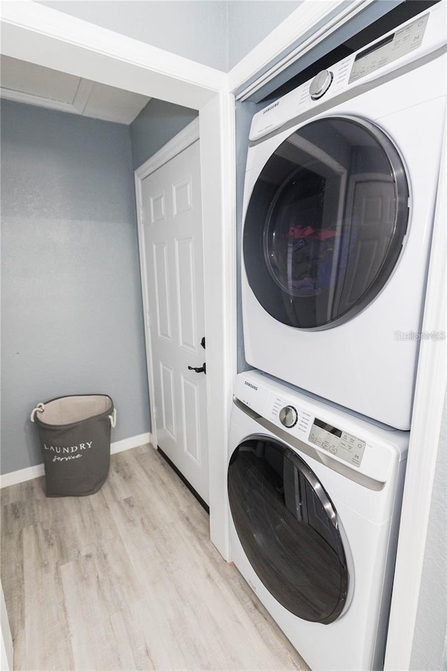 clothes washing area with light wood-type flooring and stacked washer / dryer