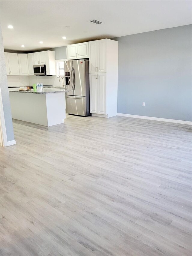 kitchen featuring white cabinetry, light hardwood / wood-style flooring, light stone counters, and appliances with stainless steel finishes