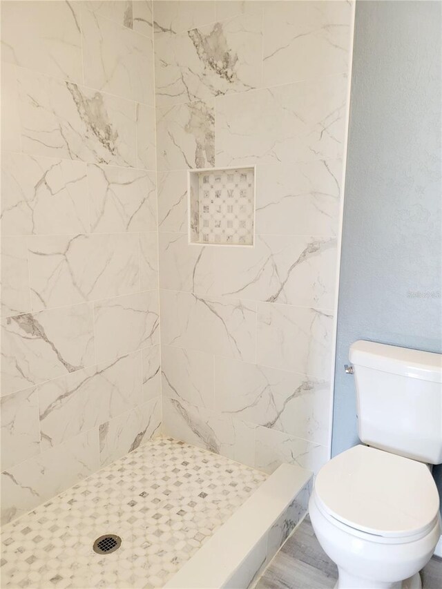 bathroom with a tile shower and toilet