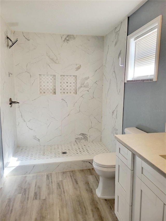 bathroom featuring tiled shower, vanity, and toilet