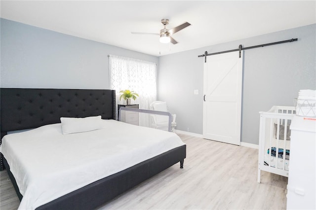 bedroom featuring a barn door, light hardwood / wood-style flooring, and ceiling fan