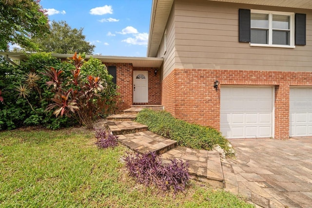 view of exterior entry with a garage and a yard