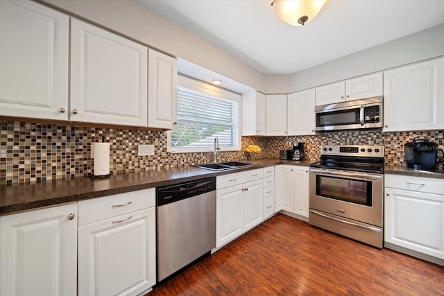 8212 Forest Cir, Seminole, FL 33776 - kitchen with stainless steel appliances, a sink, dark countertops, and white cabinets