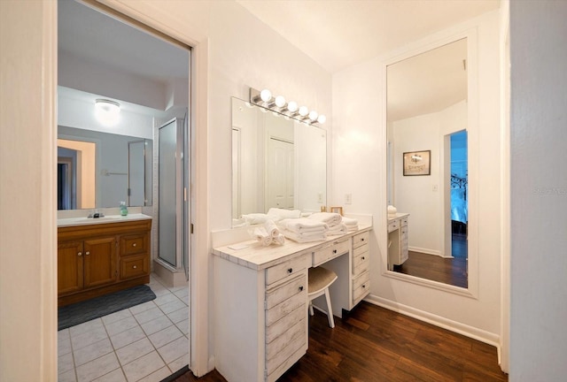 8212 Forest Cir, Seminole, FL 33776 - bathroom with two vanities, a stall shower, ensuite bath, baseboards, and wood finished floors