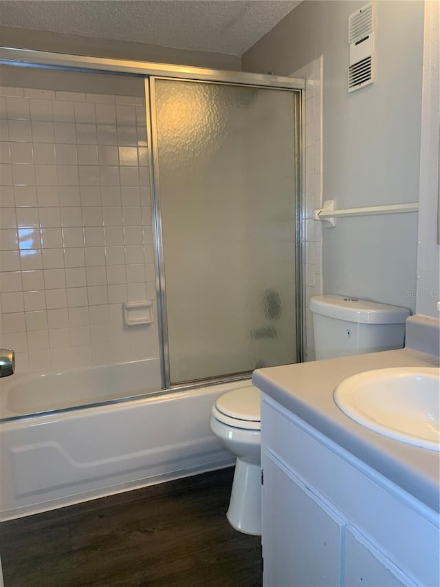 full bathroom featuring a textured ceiling, toilet, enclosed tub / shower combo, vanity, and hardwood / wood-style flooring