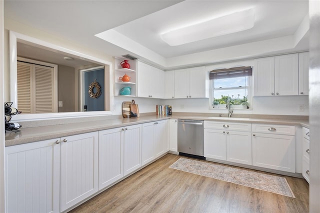 kitchen with white cabinets, dishwasher, light hardwood / wood-style flooring, sink, and a tray ceiling