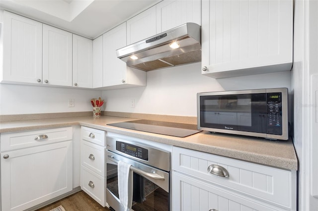 kitchen featuring dark wood-type flooring, white cabinets, appliances with stainless steel finishes, and exhaust hood