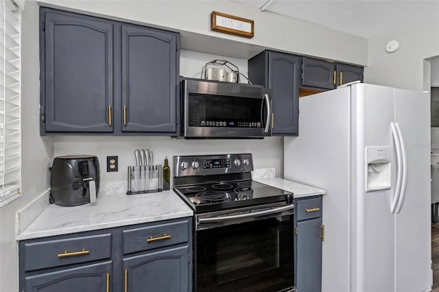 7331/2 New Jersey St, Clearwater, FL 33756 - kitchen featuring blue cabinetry, black electric range oven, light stone counters, stainless steel microwave, and white fridge with ice dispenser