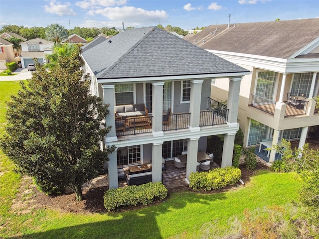 rear view of property featuring an outdoor hangout area, a balcony, and a lawn