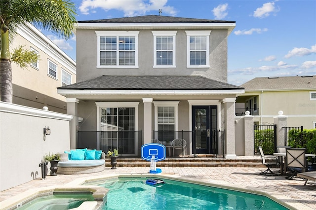 back of house with a swimming pool with hot tub and a patio area