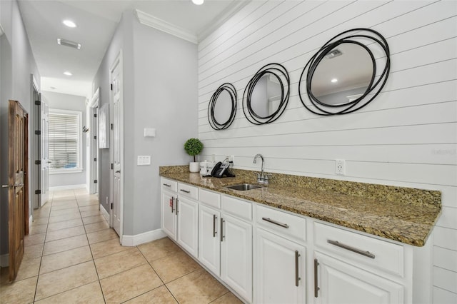 kitchen featuring dark stone counters, ornamental molding, sink, and white cabinets