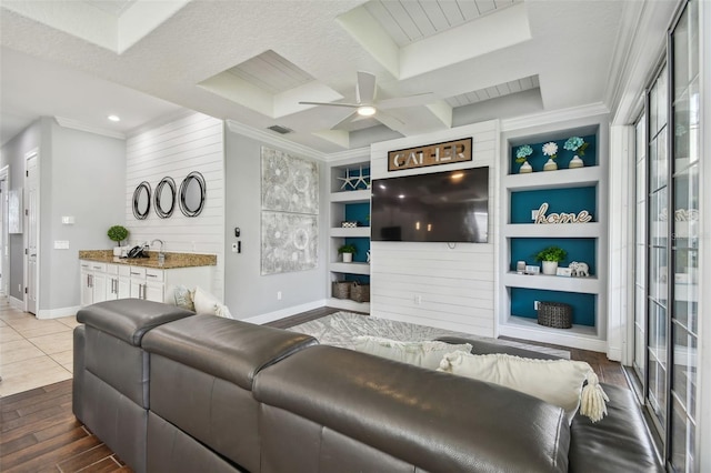 living room featuring ceiling fan, built in features, a textured ceiling, wooden walls, and hardwood / wood-style floors