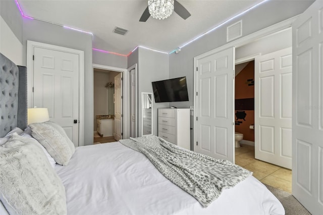 bedroom featuring ceiling fan, ensuite bath, and light tile patterned floors