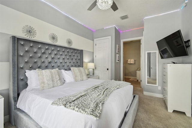 bedroom featuring ceiling fan, light colored carpet, and ensuite bathroom