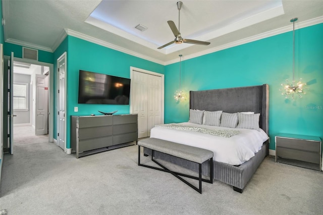 carpeted bedroom with crown molding, a tray ceiling, ceiling fan, and a closet