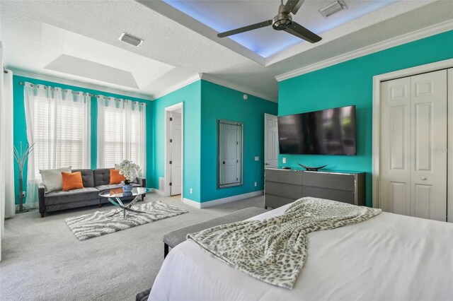 carpeted bedroom featuring a textured ceiling, crown molding, ceiling fan, and a closet