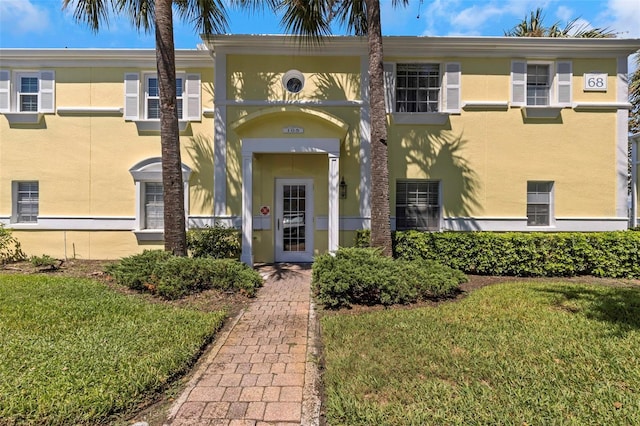 entrance to property featuring a yard and stucco siding