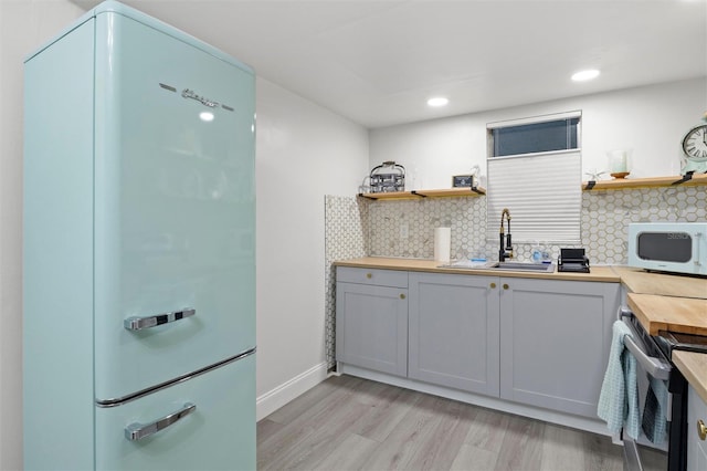 kitchen featuring sink, tasteful backsplash, wooden counters, light hardwood / wood-style floors, and white appliances