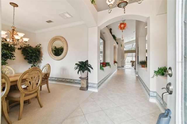 entryway with ornamental molding, a chandelier, and light tile patterned flooring