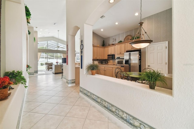 kitchen with lofted ceiling, light brown cabinets, stainless steel appliances, and light tile patterned flooring