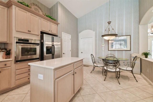 kitchen featuring pendant lighting, light tile patterned floors, a center island, appliances with stainless steel finishes, and light brown cabinets