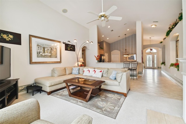 tiled living room with ceiling fan and high vaulted ceiling