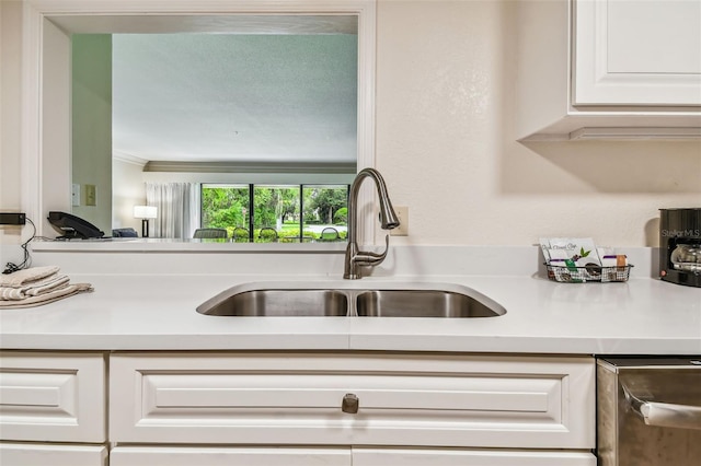 kitchen with ornamental molding, sink, and white cabinets