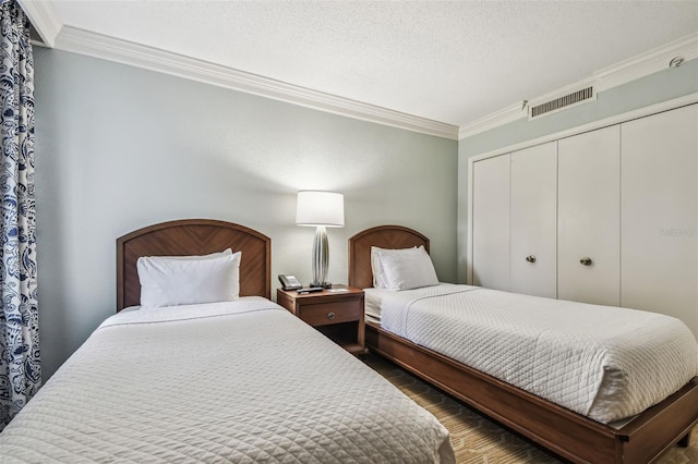 bedroom with a closet, dark hardwood / wood-style floors, crown molding, and a textured ceiling