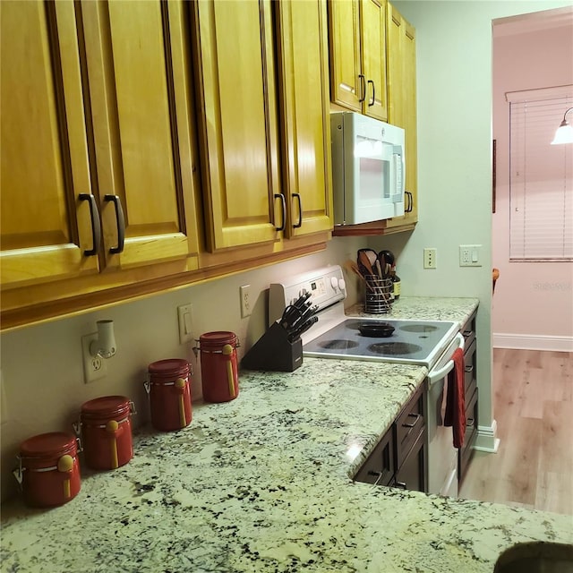 kitchen with light stone counters, light hardwood / wood-style floors, and range with electric stovetop