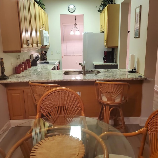 kitchen with white appliances, pendant lighting, a notable chandelier, sink, and light stone counters