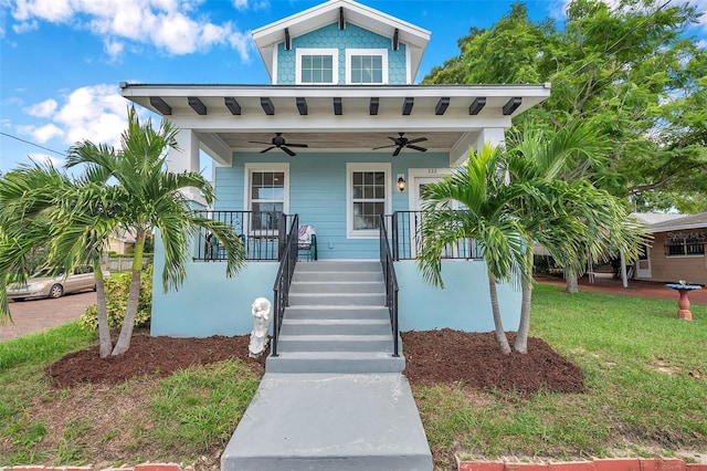 view of front of house featuring ceiling fan, a front yard, and covered porch