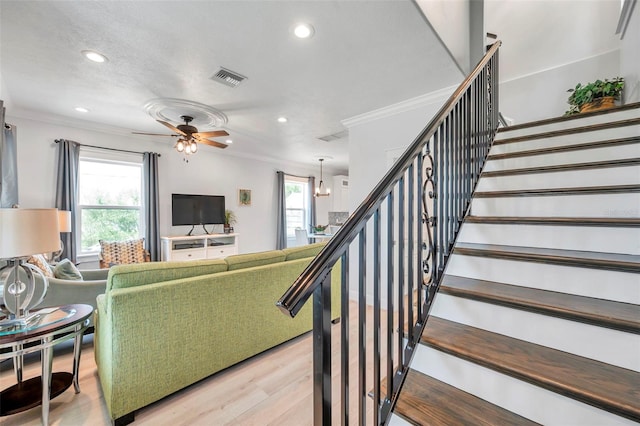 living room with ornamental molding, light wood-type flooring, and ceiling fan