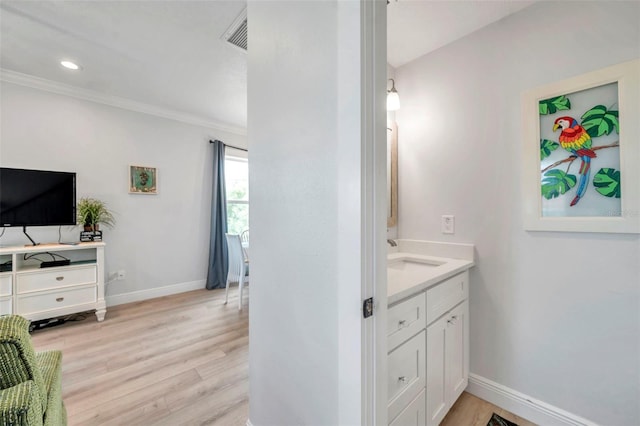 bathroom with hardwood / wood-style flooring, vanity, and crown molding