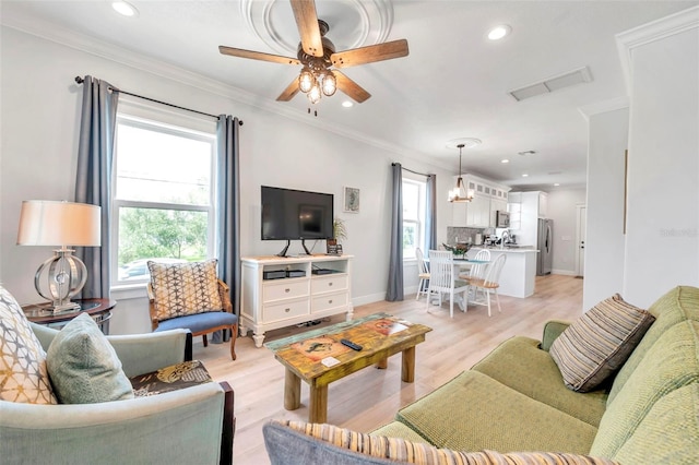 living room featuring ceiling fan with notable chandelier, light wood-type flooring, and crown molding